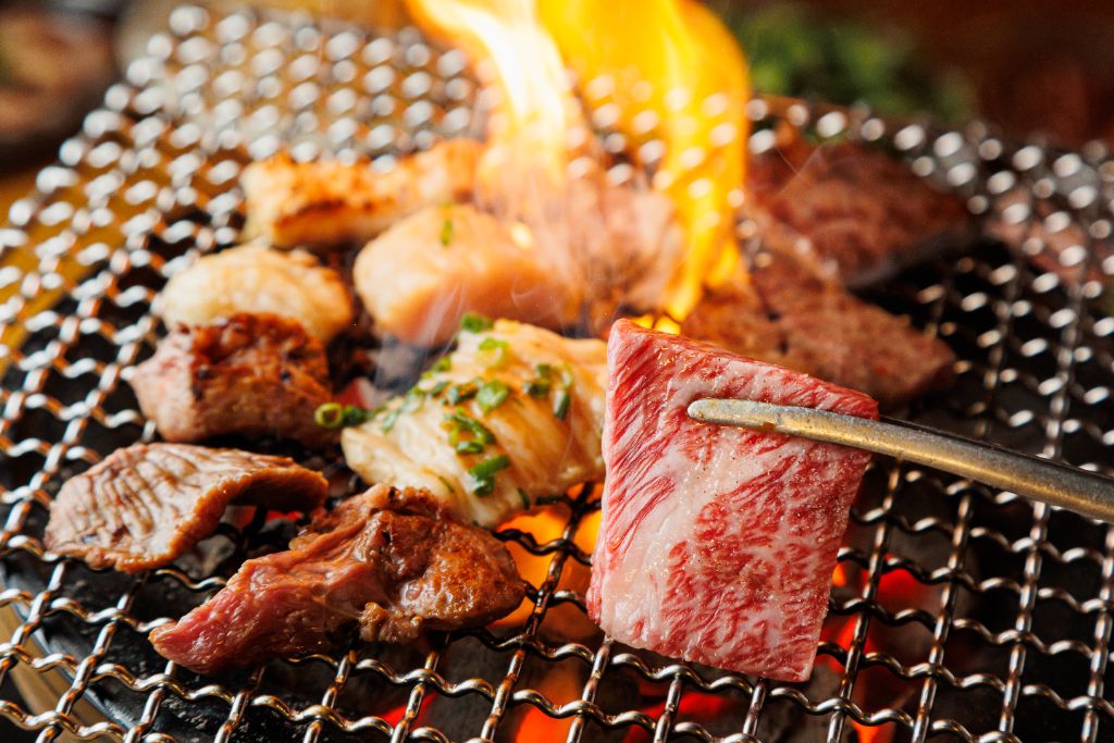 炎が上がる網の上で焼かれるホルモンと焼肉